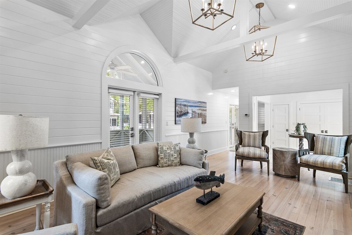 A spacious living room with a large sofa, two armchairs, a coffee table, and a chandelier.