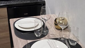A neatly set dining table with plates, cutlery, and glasses, a wine glass, and a decorative gold sphere.