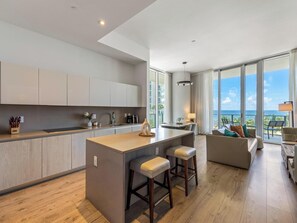 Une cuisine moderne avec un îlot central, un coin repas offrant une vue agréable et un salon avec un canapé et une table.