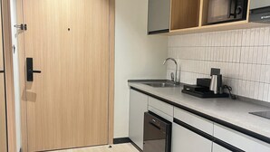 Una cocina moderna con puerta de madera, lavavajillas integrado, microondas y un lavabo.
