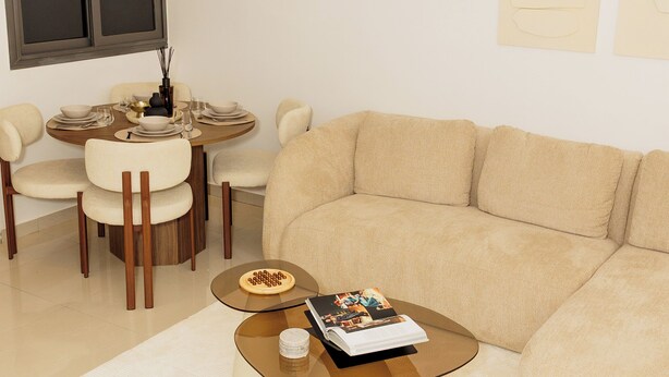 A modern living room with a beige sofa, a round coffee table, and a dining table set for four. - Chic & Moderne Studio at Sacré-Cœur 1, Dakar (Dakar)