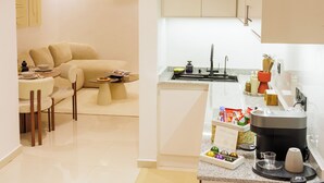 A modern kitchen with white cabinets, a coffee machine, and a small dining area with a sofa and table. - Chic & Moderne Studio at Sacré-Cœur 1, Dakar (Dakar)