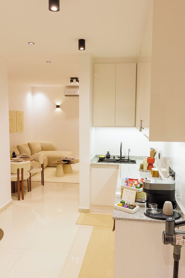 A modern kitchen with white cabinets, a coffee machine, and a small dining area with a sofa and table. - Stylish & modern studio at Sacré-Cœur 1, Dakar (Dakar)