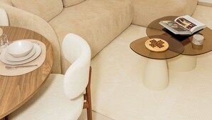 A modern living room with a beige sofa, a wooden dining table with chairs, and a small coffee table with a magazine and a bowl. - Chic & Moderne Studio at Sacré-Cœur 1, Dakar (Dakar)