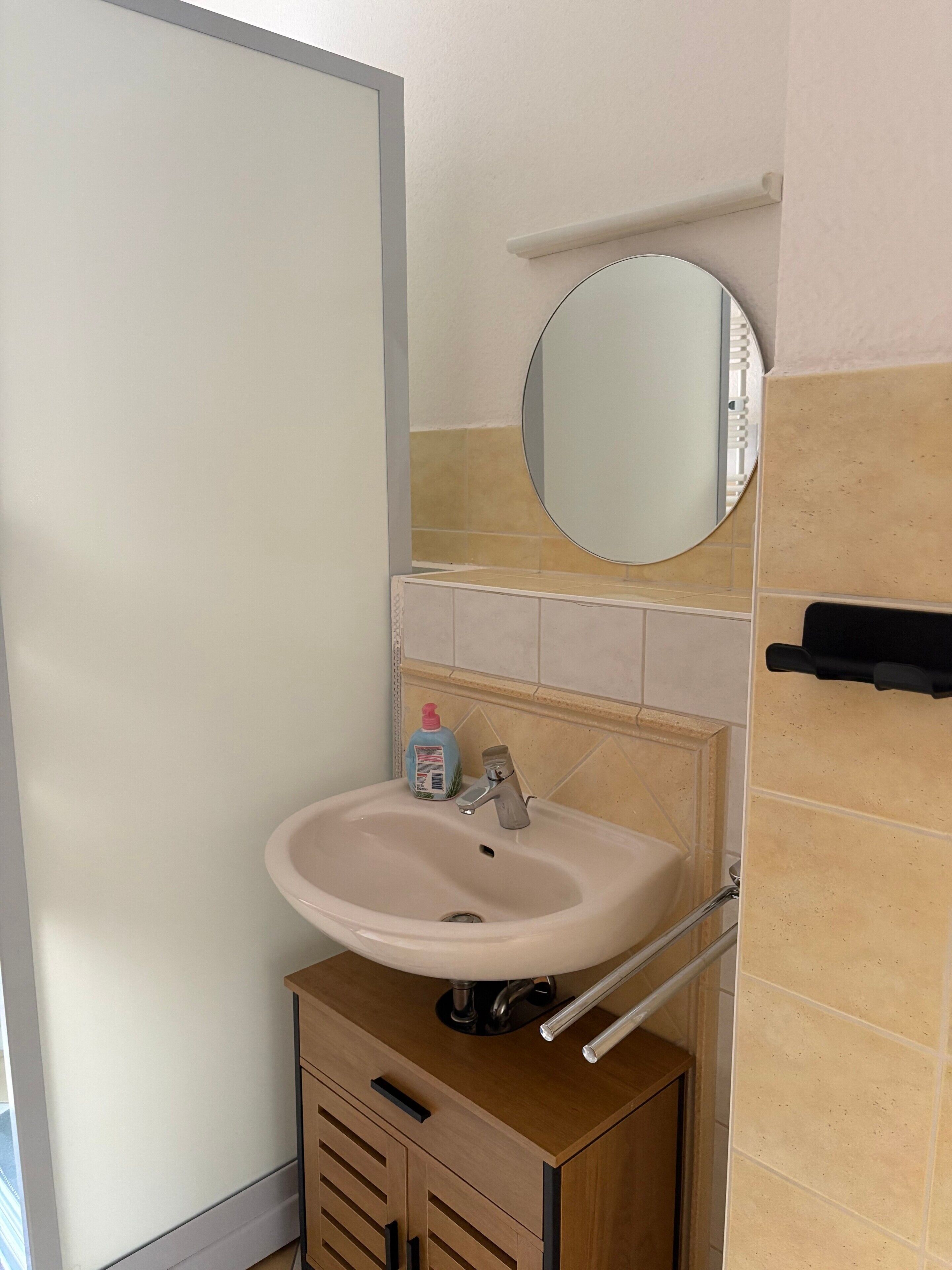 Un bagno con lavandino, specchio e portasciugamani.
