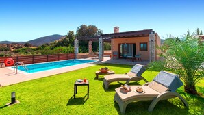 Ein Poolbereich mit freiem Blick auf das Schwimmbecken, Liegestühle und eine Pergola.