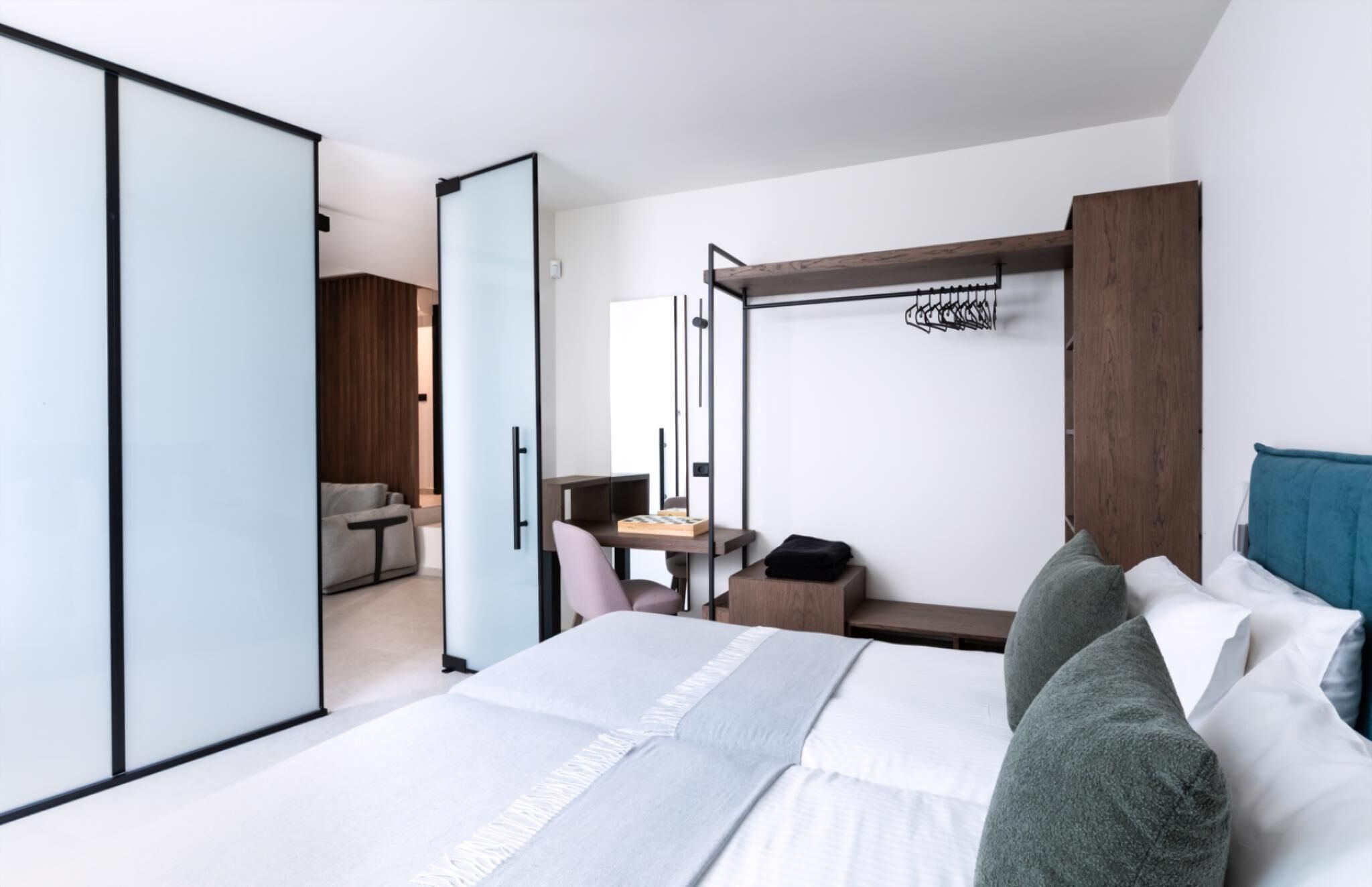 Ein modernes Hotelzimmer mit Bett, Schreibtisch, Kleiderschrank und Garderobe.