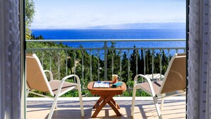 Ein Balkon mit zwei Stühlen und einem kleinen Tisch, der einen schönen Blick auf das Meer und die grüne Landschaft bietet.