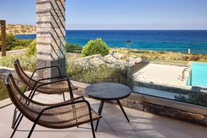 A terrace with wicker chairs and a small table overlooking a pool and the sea. - Stunning, Contemporary Waterfront Villa with Heated Infinity Pool & Breakfast (Sitia)