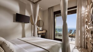 Una camera da letto con un letto grande, una TV a schermo piatto, una scrivania e vista sull'oceano.