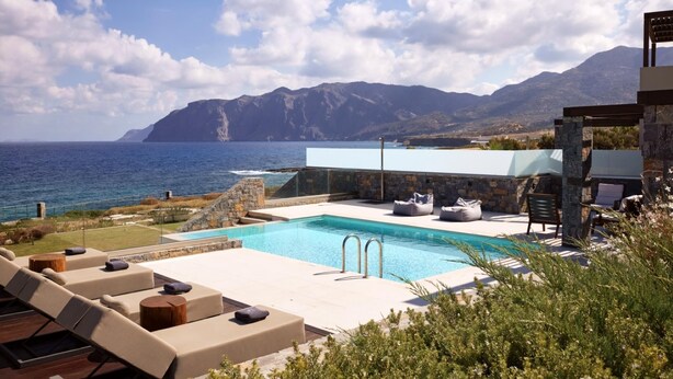 Area piscina con lettini e vista sul mare e sulle montagne.