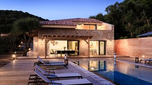 A modern house with a swimming pool, outdoor seating, and a dining area. - Stylish Villa with Heated Pool steps from the Beach and Restaurant (Olmeto)