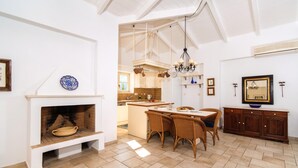 Un'ampia cucina con zona pranzo, caratterizzata da un camino, mobili in legno e un lampadario.