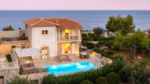 Una casa a due piani con piscina, area relax esterna e vista sul mare.