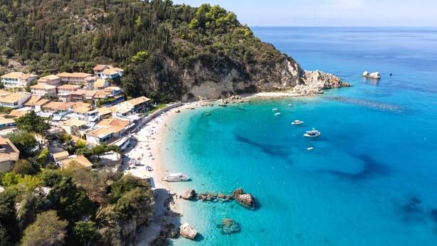 Una località costiera con spiaggia, acque cristalline e affioramenti rocciosi.