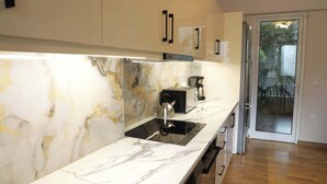 Uma cozinha moderna com bancadas de mármore, fogão embutido e máquina de café.