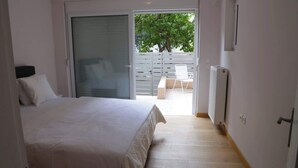 Quarto com cama, porta de vidro deslizante para uma varanda e radiador.