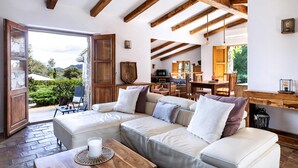 Una sala de estar acogedora con un sofá modular, vigas de madera, una zona de comedor y vistas al exterior.