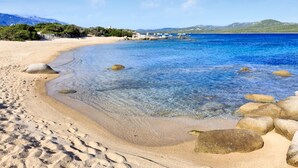 A beach with clear water, rocks, and a distant view of mountains. - Stylish Signature Villa with Heated Pool close to the Beach (Pianottoli-Caldarello)