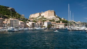 A coastal town with a historic fort on a hill, marina with boats, and buildings along the waterfront. - Stylish Signature Villa with Heated Pool close to the Beach (Pianottoli-Caldarello)