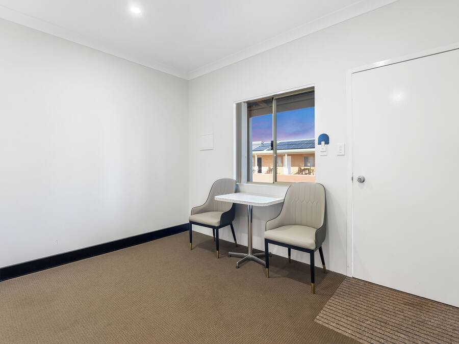 A hotel room with a large window, a small table, two chairs, and a carpeted floor.