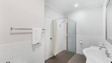 Um banheiro moderno com box de vidro, pia branca e porta-toalhas.