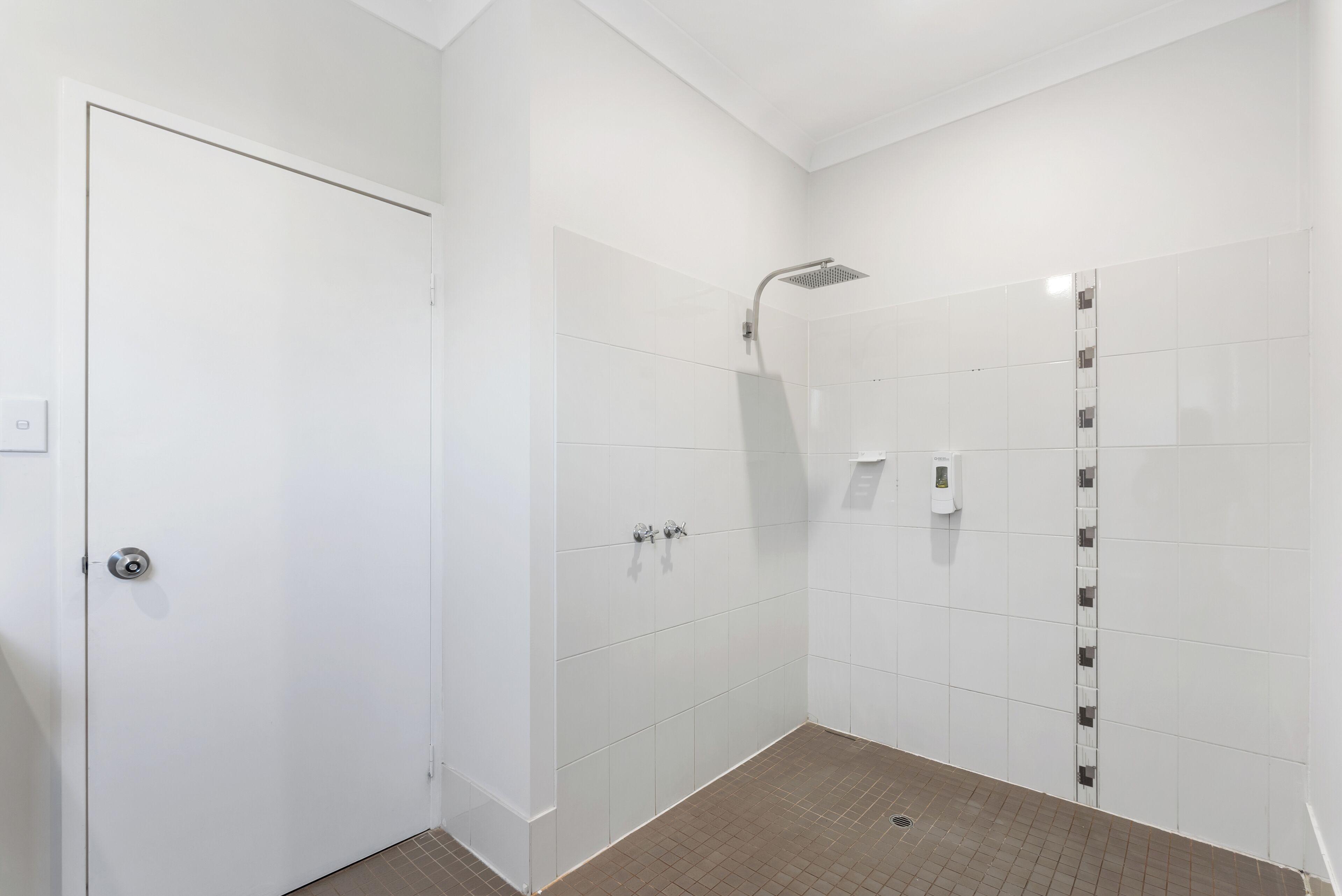 A modern bathroom with white walls, a shower area, and a door.