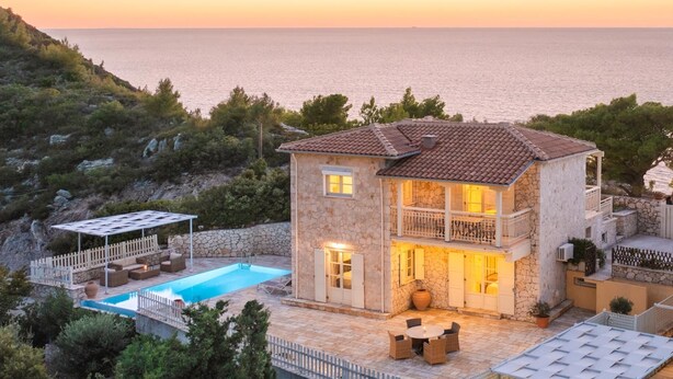 A two-story stone house with a swimming pool, outdoor seating, and a view of the sea at sunset. - Cosy Villa with Sea-and-Mountain Views near Agios Nikitas (Lefkada)