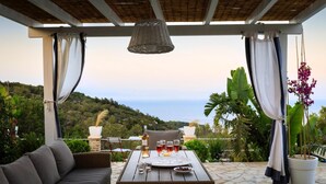 Una terrazza esterna con tavolo apparecchiato per consumare pasti, una poltrona e un lampadario.