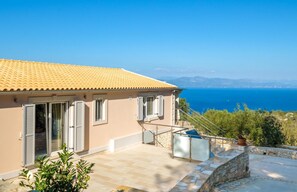 A coastal property with a tiled roof, a stone wall, and a view of the sea. - Villa Strati - Spacious Villa with Wonderful Sea Views near Gaios and Beach (Paxos)