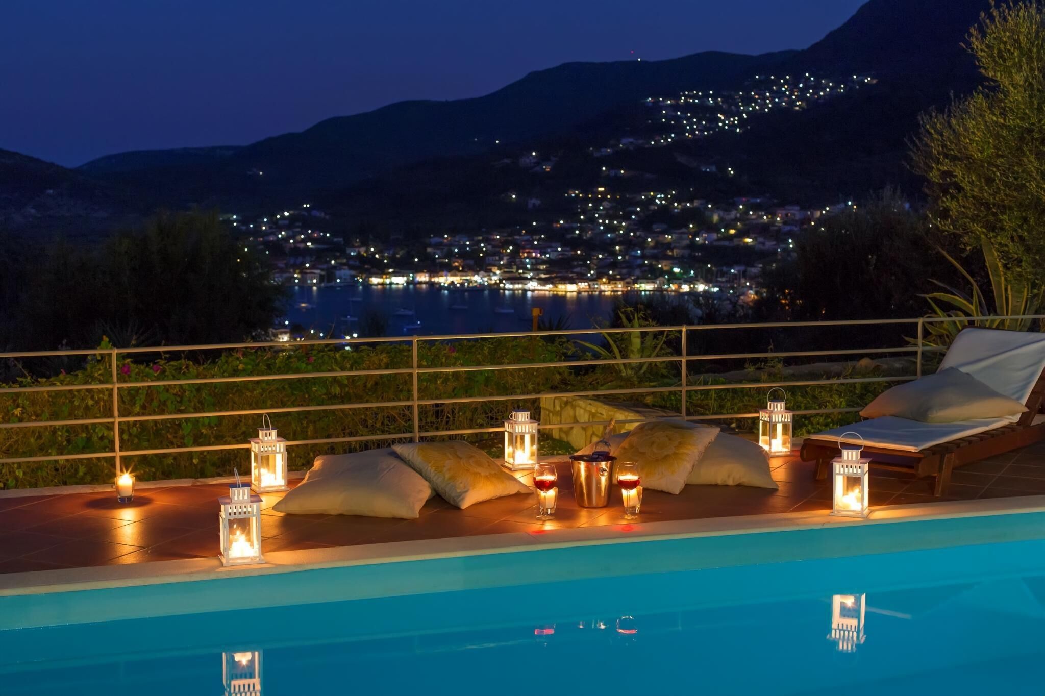 A poolside area with lounge chairs, cushions, and lanterns.
