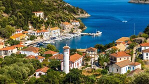 Un village côtier doté d’une architecture traditionnelle, d’un port de plaisance avec des bateaux et d’une église.