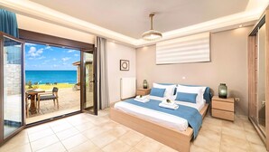 Une chambre dotée d’un grand lit, offrant une vue sur la mer, et d’un patio aménagé avec du mobilier d’extérieur.