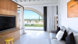 Moderni olohuone, jossa on litteänäyttöinen televisio, sohva ja suuri ikkuna, josta avautuu näkymä puutarhaan.