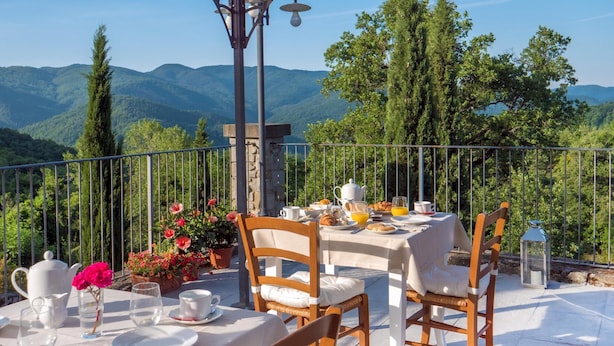 A terrace with a table set for breakfast, overlooking a mountainous landscape. - Villa Mille Desideri (Arezzo)