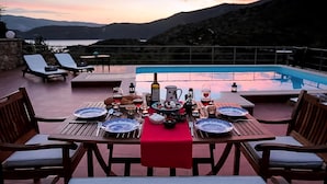 Mesa lista para la cena, con una piscina y montañas al fondo.