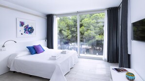 Ein modernes Schlafzimmer mit einem großen Bett, einem Nachttisch, einem Fenster mit Vorhängen und Blick auf Bäume.