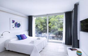 Quarto moderno com uma cama grande, mesa de cabeceira, janela com cortinas e vista para árvores.