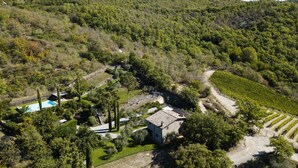 Ein Steinhaus, umgeben von Weinbergen und einem Swimmingpool.