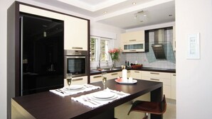 Una cucina moderna con un'isola in legno scuro, mobili bianchi ed elettrodomestici in acciaio inossidabile.