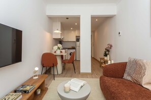 Ein modernes Wohnzimmer mit einer Couch, einem Couchtisch, einem Fernseher und einem Essbereich mit Stühlen und einem Tisch.
