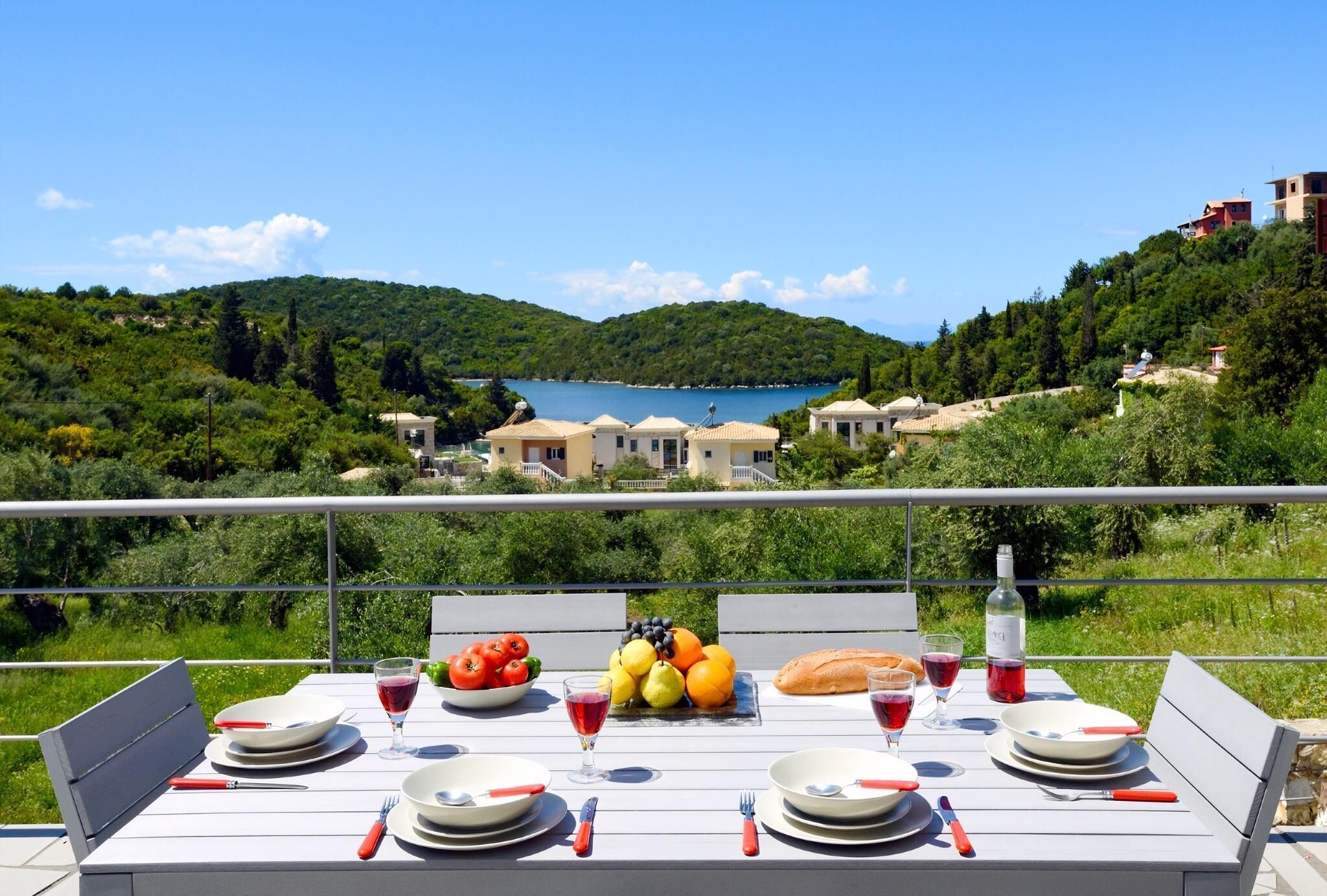 A table set for dining with a scenic view of a lake and hills.