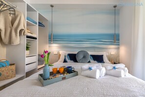 Habitación de hotel con cama, armario, bandeja con alimentos para el desayuno y un cuadro marino en la pared.