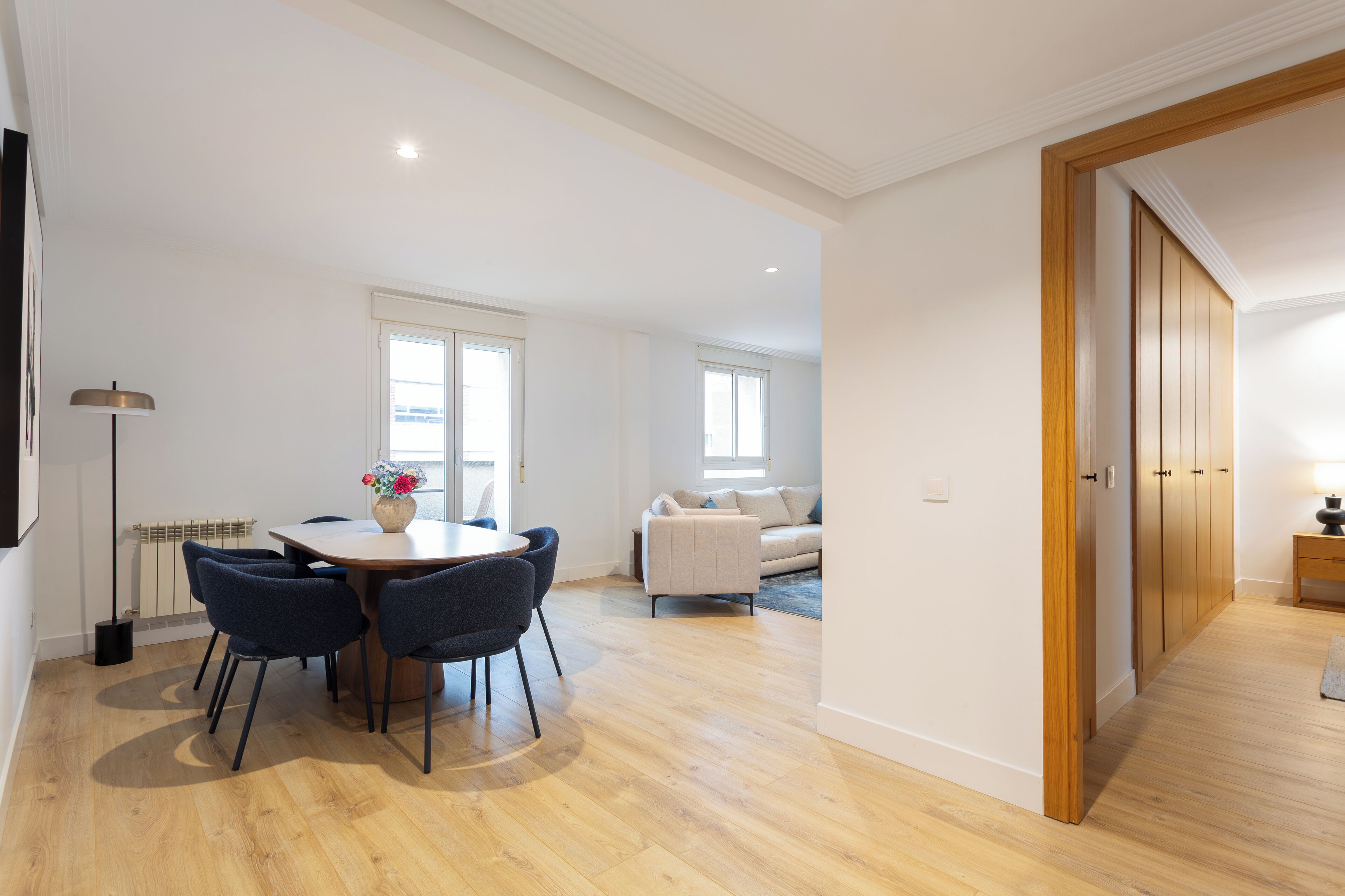 Ein modernes Wohnzimmer mit Essbereich, Holzboden und einem großen Fenster, das für natürliches Licht sorgt.