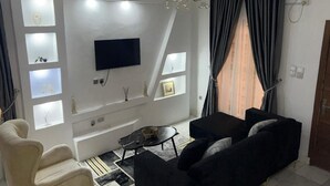 Una sala de estar moderna con televisor de pantalla plana, una araña y un sofá.