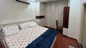 A hotel room with a bed, an air conditioning unit, a wardrobe, a chair, and a window with curtains. - Atlas Homes Penthouse 1BHK Jacuzzi @ Hitech City (Hyderabad)