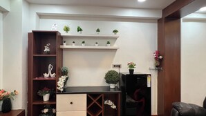 A modern living room with a wooden cabinet, a black sofa, and a small black refrigerator. - Atlas Homes Penthouse 1BHK Jacuzzi @ Hitech City (Hyderabad)