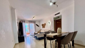 Una sala de estar moderna con comedor, un sofá, un televisor y un elemento decorativo en la pared.