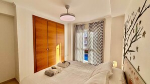 Un dormitorio con cama, armario, ventilador de techo y un mural de un árbol en la pared.