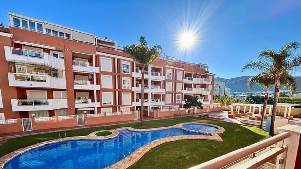 Un hotel con piscina, varios balcones y vistas a las montañas.
